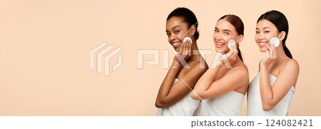 Facial Skincare Concept. Three Diverse Girls In Bath Towels Holding Cotton Pads Near Face Posing Over White Studio Background. 124082421