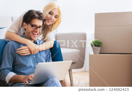 Man And Woman Relaxing Sitting With Laptop After Moving Apartment. Free Space Man And Woman Relaxing Sitting With Laptop After Moving Apartment. Free Space 124082423