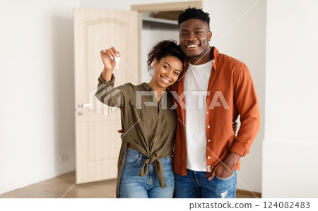 Real Estate. Cheerful African American Spouses Showing New House Key Smiling To Camera, Embracing Standing Among Moving Cardboard Boxes At Home. Relocation, Apartment Ownership And Family Housing Real Estate. Cheerful African American Spouses Showing New House Key Smiling To Camera, Embracing Standing Among Moving Cardboard Boxes At Home. Relocation, Apartment Ownership And Family Housing 124082483