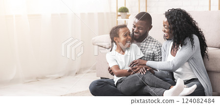 African american family having fun at home, parents tickling their daughter and laughing together. 124082484