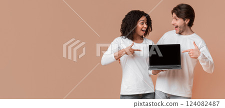Great Website. Excited interracial couple pointing at laptop with black screen for mockup, standing over yellow background with free space Great Website. Excited interracial couple pointing at laptop with black screen for mockup, standing over yellow background with free space 124082487