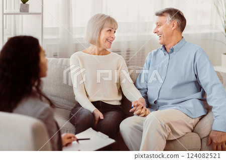 Love And Family Concept. Happy mature couple holding hands, looking at each other at psychologist office after session Love And Family Concept. Happy mature couple holding hands, looking at each other at psychologist office after session 124082521