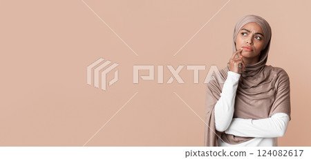 Portrait of doubtful afro muslim woman in headscarf touching chin, overthinking options and looking away over yellow background Portrait of doubtful afro muslim woman in headscarf touching chin, overthinking options and looking away over yellow background 124082617