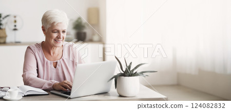 Mature attractive business lady enjoying her job, working from home with laptop, free space Mature attractive business lady enjoying her job, working from home with laptop, free space 124082832