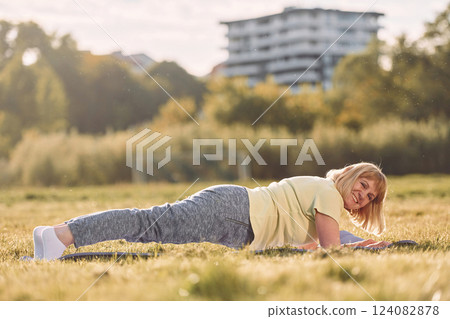 On yoga mat. Senior woman having nice weekend outdoors on the field at sunny day On yoga mat. Senior woman having nice weekend outdoors on the field at sunny day 124082878
