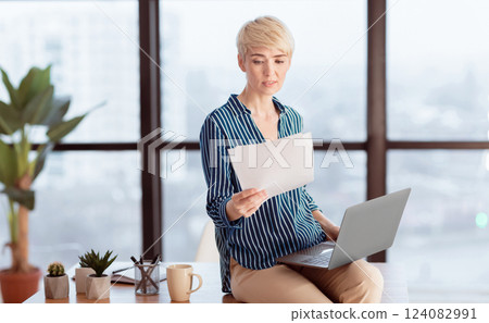 Business Lady With Laptop Reading Papers And Documents Sitting On Desk In Modern Office. Entrepreneurship And Occupation Concept. 124082991