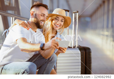 Couple using phone, making video call in airport, waiting for departure 124082992