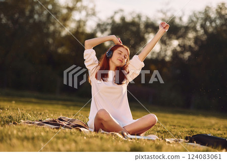 Moving to the music. Young girl is on the field at sunny daytime having nice weekend Moving to the music. Young girl is on the field at sunny daytime having nice weekend 124083061