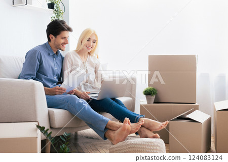 Husband And Wife Using Laptop Looking Design Project Sitting On Couch In Own House. Moving Into New Home. Copy Space 124083124