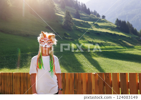 Cute young little kid girl boy wear cat furry mask enjoy have fun playing outdoors alpine valley street park. Child therian wild animal character trendy fan culture. Teenager social expression hobby 124083149