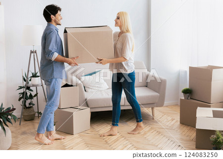 Happy Spouses Carrying Moving Box Together Into New Home. Ready For Relocation. Empty Space Happy Spouses Carrying Moving Box Together Into New Home. Ready For Relocation. Empty Space 124083250