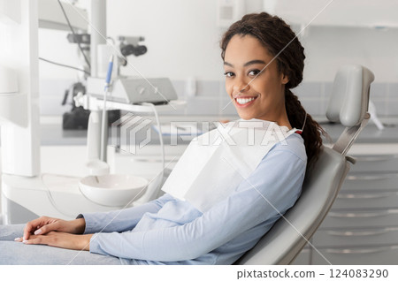 Young black lady sitting in dentist chair and smiling at camera, copy space Young black lady sitting in dentist chair and smiling at camera, copy space 124083290
