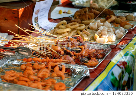 Street food festival in Europe. Asian street food, grilled seafood skewers on counter, fast food dish from street vendor. Shrimp, squid, octopus ready to eat. Street food festival in Europe. Asian street food, grilled seafood skewers on counter, fast food dish from street vendor. Shrimp, squid, octopus ready to eat. 124083330