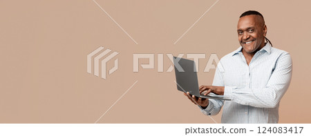 Modern job lifestyle. Mature african american man working on laptop online, using internet, orange background 124083417