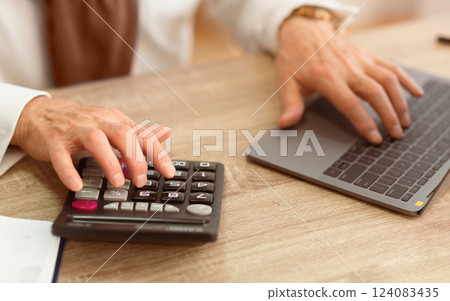 Technology Evolution. Closeup Of Old Man's Hands Using Calculator And Laptop PC Sitting In Office. Selective Focus, Cropped 124083435