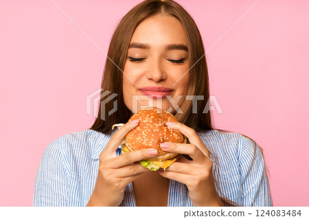Cheat Meal. Happy Girl Eating Burger Standing Over Yellow Background. Studio Shot 124083484