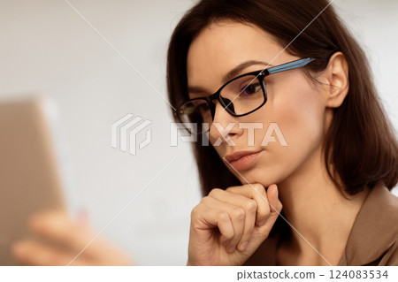 Office Worker. Close up portrait of beautiful woman in glasses working on personal computer at office, holding tablet Office Worker. Close up portrait of beautiful woman in glasses working on personal computer at office, holding tablet 124083534