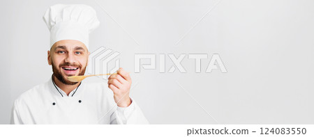 Chef Guy Tasting Dish Holding Spoon Smiling To Camera Posing Standing On Gray Studio Background. Gourmet Concept. Panorama, Empty Space 124083550