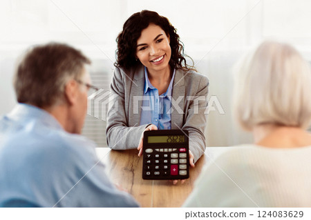 Senior couple receiving financial advice from mexican insurance consultant who showing them calculator Senior couple receiving financial advice from mexican insurance consultant who showing them calculator 124083629