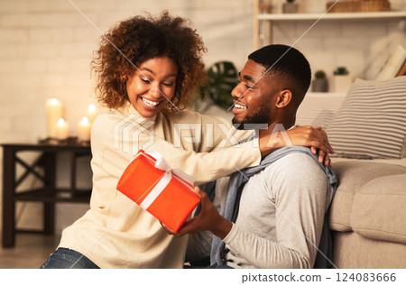 Happy New Year. Black couple celebrating Christmas at home, man giving present to wife Happy New Year. Black couple celebrating Christmas at home, man giving present to wife 124083666