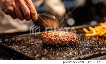 A chef expertly seasons a sizzling burger on a grill, surrounded by a colorful array of fries, during dinner service. 124084216