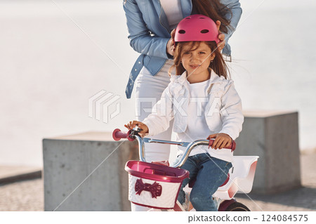 Having fun together. Mother with her young daughter is with bicycle outdoors together 124084575