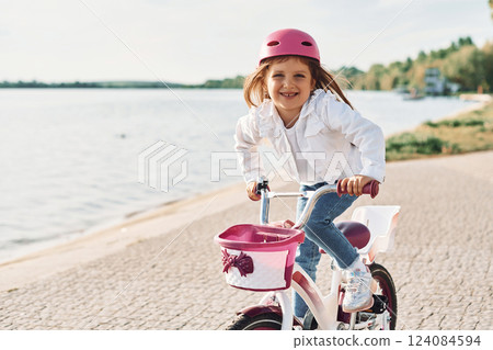 Active weekend time spending. Happy little girl riding a bicycle outdoors in summer 124084594