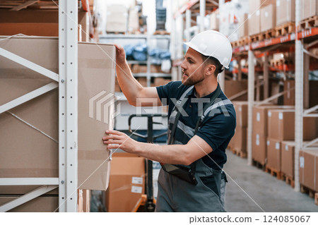 Checking the box. Employee in uniform is working in the storage at daytime 124085067