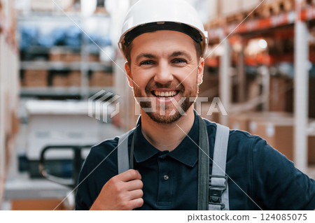 Smiling for the camera. Employee in uniform is working in the storage at daytime Smiling for the camera. Employee in uniform is working in the storage at daytime 124085075