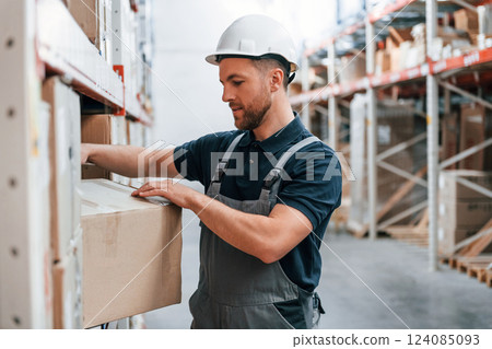 Manager is in the store. Employee in uniform is working in the storage at daytime 124085093