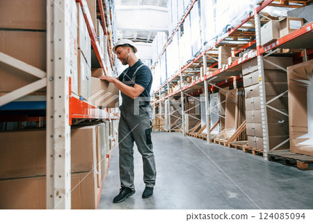 Taking out the box. Employee in uniform is working in the storage at daytime 124085094