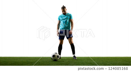 Focused football player standing with ball at feet on green field, preparing for strategic play, showcasing readiness and control. Focused football player standing with ball at feet on green field, preparing for strategic play, showcasing readiness and control. 124085168