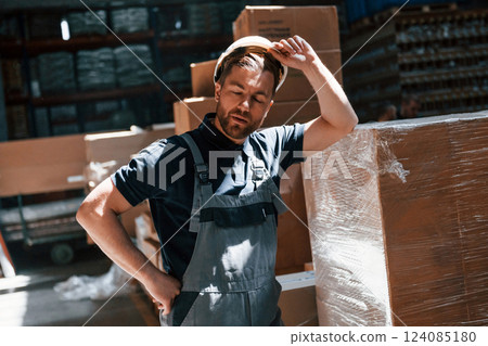 Tired employee in uniform is working in the dark storage 124085180