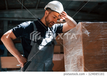 Tired employee in uniform is working in the dark storage 124085181