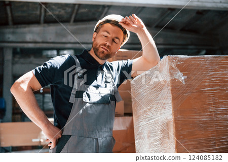 Tired employee in uniform is working in the dark storage Tired employee in uniform is working in the dark storage 124085182