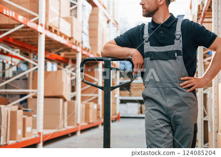 With platform trolley. Employee in uniform is working in the storage at daytime 124085204