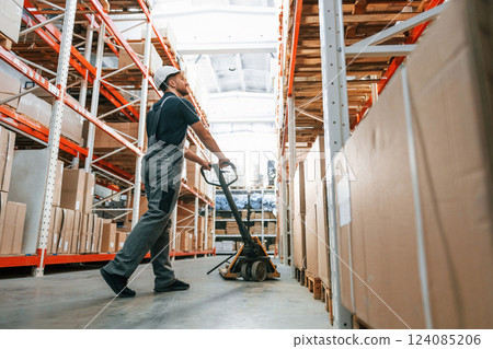 With platform trolley. Employee in uniform is working in the storage at daytime 124085206