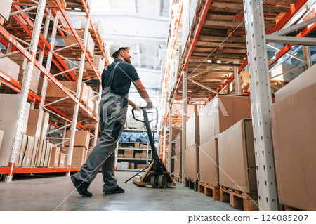 With platform trolley. Employee in uniform is working in the storage at daytime 124085207