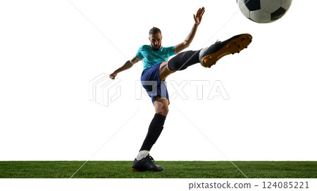 Dynamic photo of football athlete with focused expression executing powerful shot, fully stretched, kicking ball with precision. Dynamic photo of football athlete with focused expression executing powerful shot, fully stretched, kicking ball with precision. 124085221