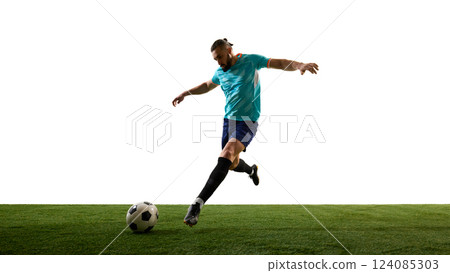 Dynamic photo of young football athlete, dressed blue uniform, training kicks ball in motion on green stadium against white background. 124085303