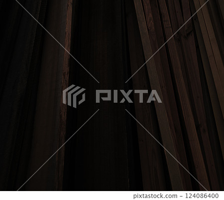 Background image of lots of dark brown lumber leaning against a wall 124086400