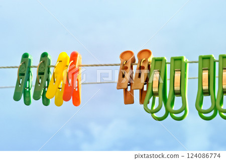 colored laundry clothespins of plastic, with metal clamping as spring). hanging on clothesline twine on open air (against overcast sky) colored laundry clothespins of plastic, with metal clamping as spring). hanging on clothesline twine on open air (against overcast sky) 124086774