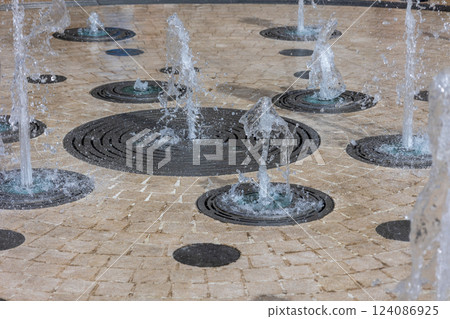 Interactive circular water fountain with bubbling jets on paved surface Interactive circular water fountain with bubbling jets on paved surface 124086925