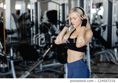 Athletic woman wearing headphones posing in the gym 124087258