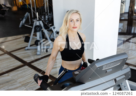 Determined sportswoman running on treadmill during fitness workout in gym 124087261