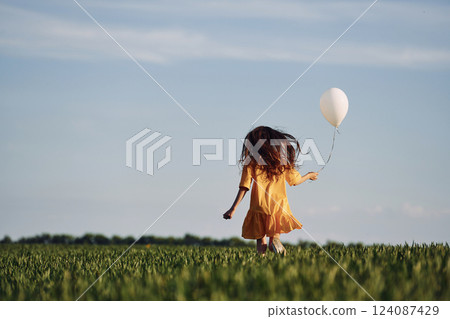 Running with balloon in hand. Happy girl have a walk outdoors on the field at summer Running with balloon in hand. Happy girl have a walk outdoors on the field at summer 124087429
