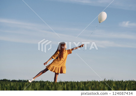 Playing with balloon. Happy girl have a walk outdoors on the field at summer Playing with balloon. Happy girl have a walk outdoors on the field at summer 124087434