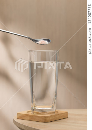 A spoon of Himalayan salt is being added to a glass of drinking water. 124087788