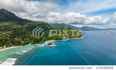 Coastal green hills with a turquoise ocean, small village structures, and sandy shorelines. Seychelles, Mahe. Coastal green hills with a turquoise ocean, small village structures, and sandy shorelines. Seychelles, Mahe. 124088098