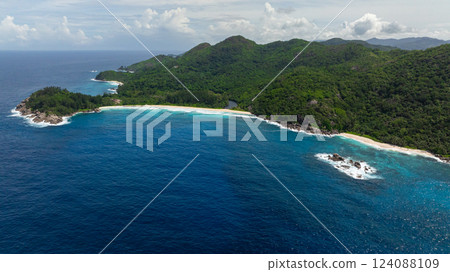 The pristine coastline is bordered by a lush rainforest and dotted with rocky outcrops along the shore. Seychelles, Mahe. The pristine coastline is bordered by a lush rainforest and dotted with rocky outcrops along the shore. Seychelles, Mahe. 124088109